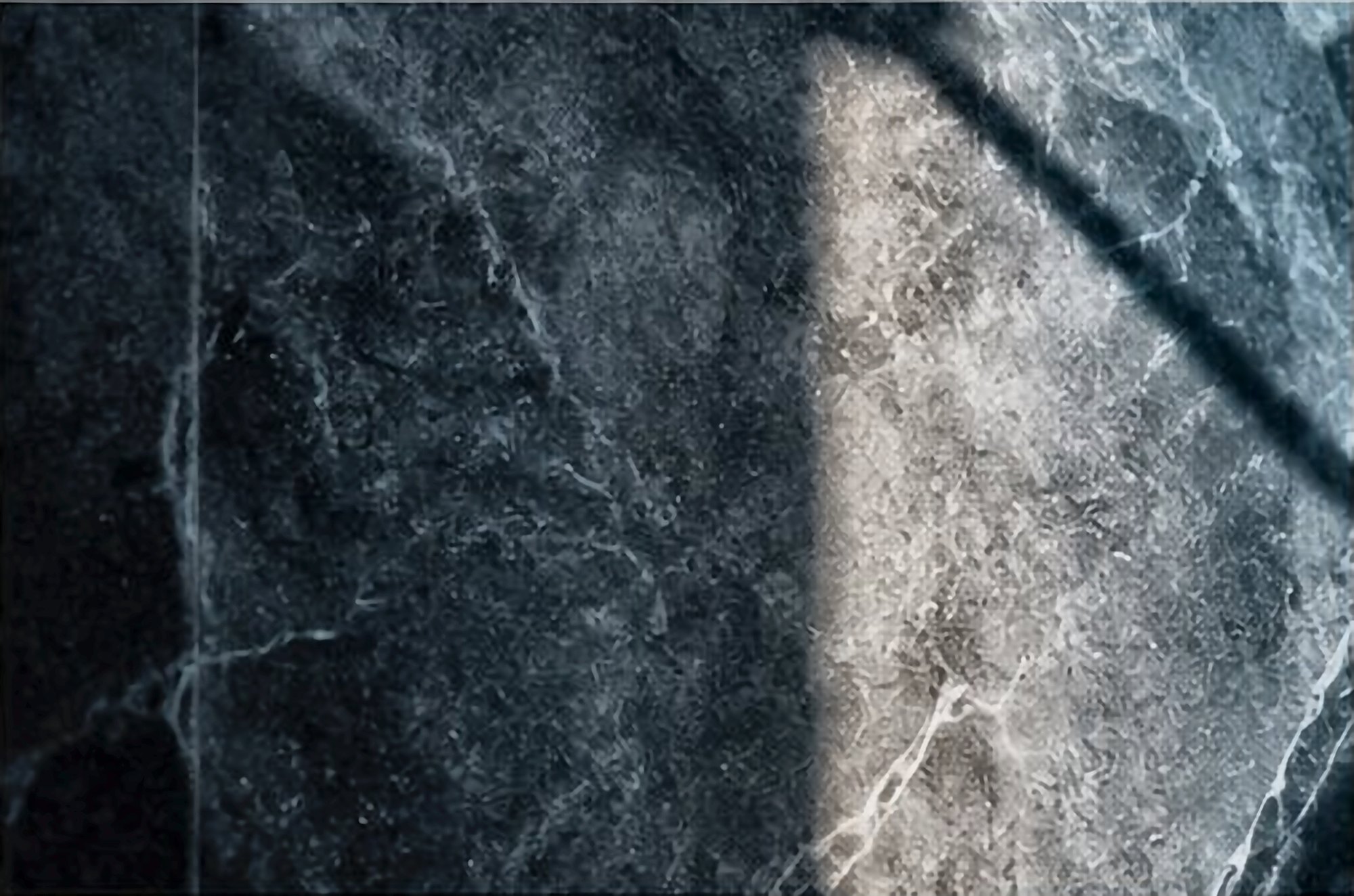 Dark veined marble lit by a shaft of light